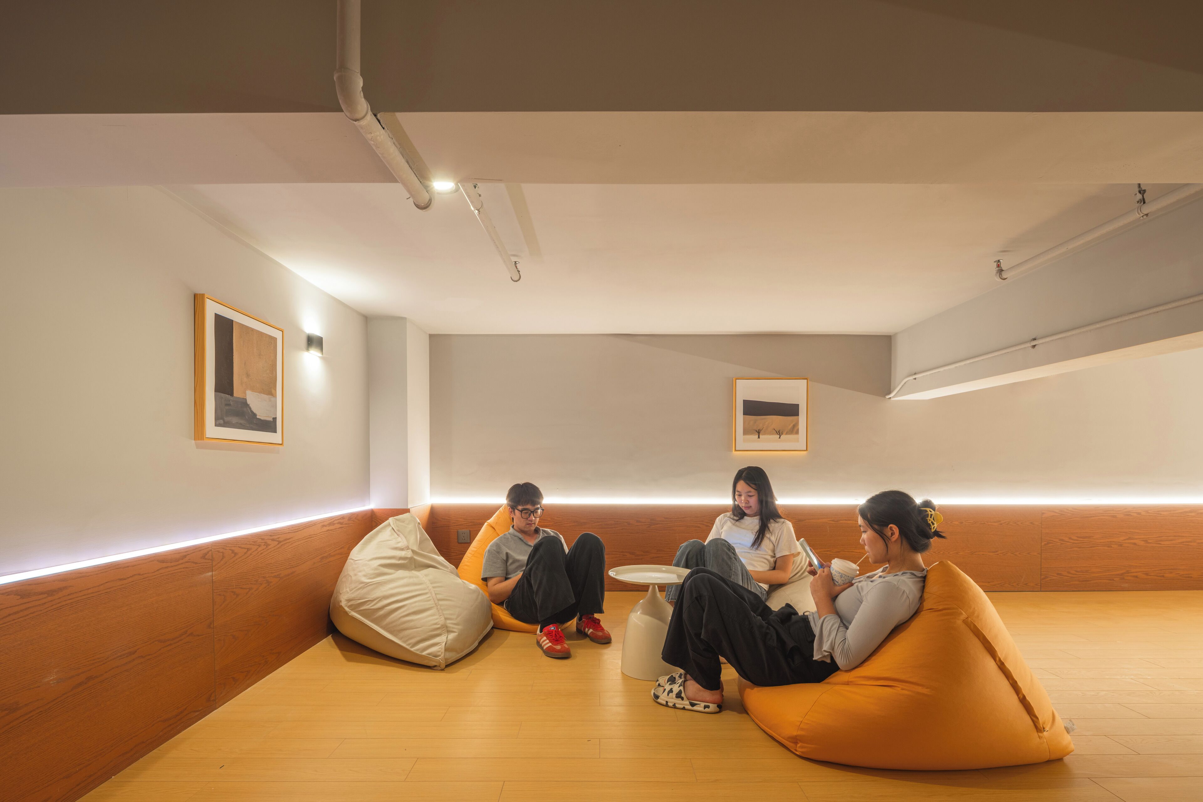 A modern interior with a wooden floor, white walls, and a low wooden bench along the wall.