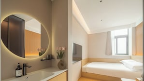 Una camera d'albergo moderna con un grande specchio, un comodino, un letto e una finestra con tende.