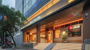 Un hotel moderno con un ingresso evidente, area salotto esterna e un cartello del ristorante ben visibile.