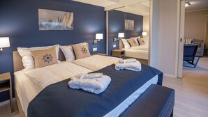 A hotel room with a large bed, two bedside tables, a bench, and a mirror.