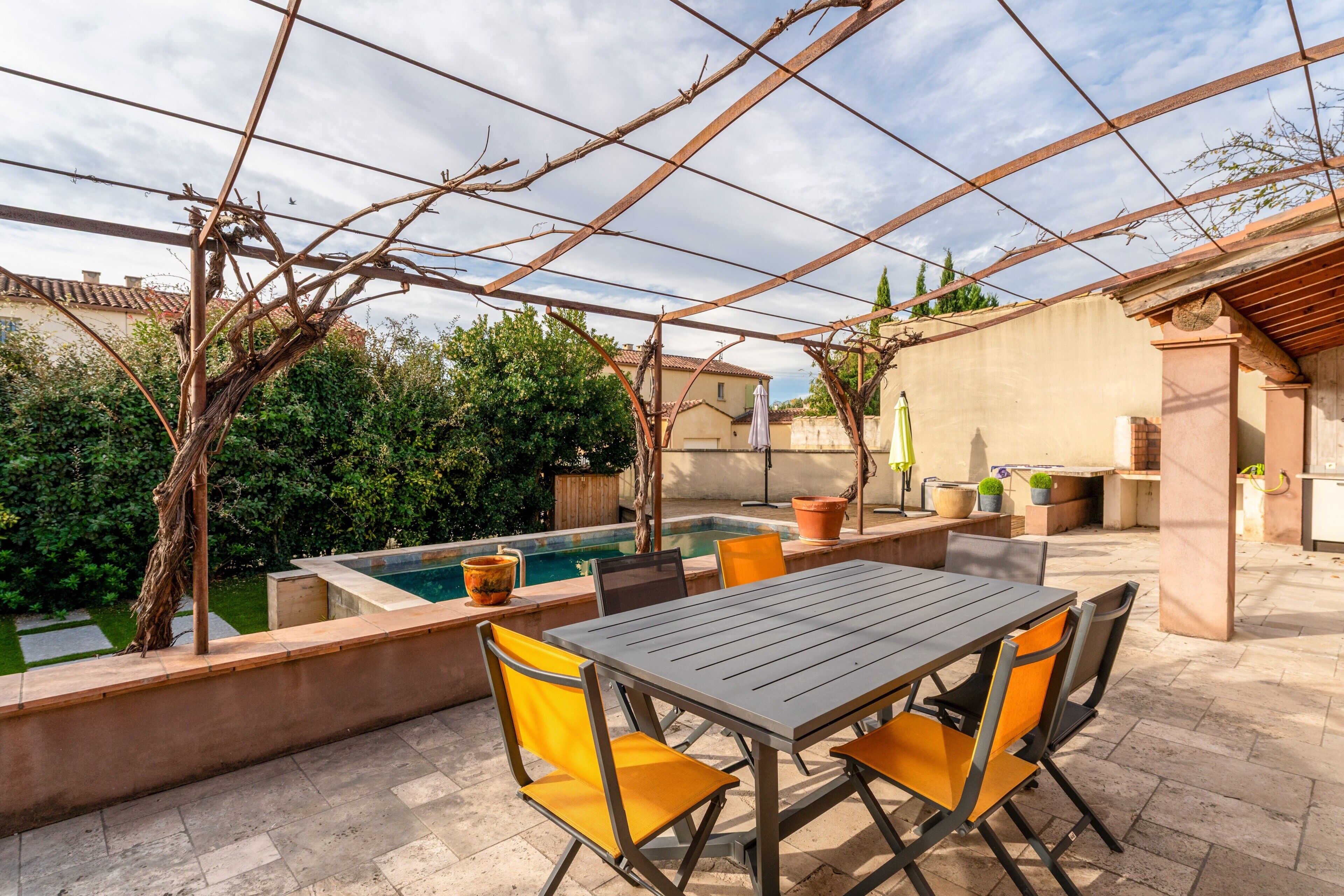Une terrasse extérieure avec une table et des chaises, une piscine et des plantes en pot.