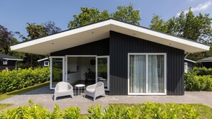 A modern house with a covered patio, a sliding glass door, and a well-maintained garden. - Peaceful Stay Near Trails (Veldhoven)