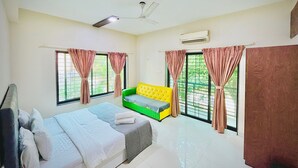 A bedroom with a bed, a sofa, and two windows with curtains. - Hotel Saiom Palace (Raipur)