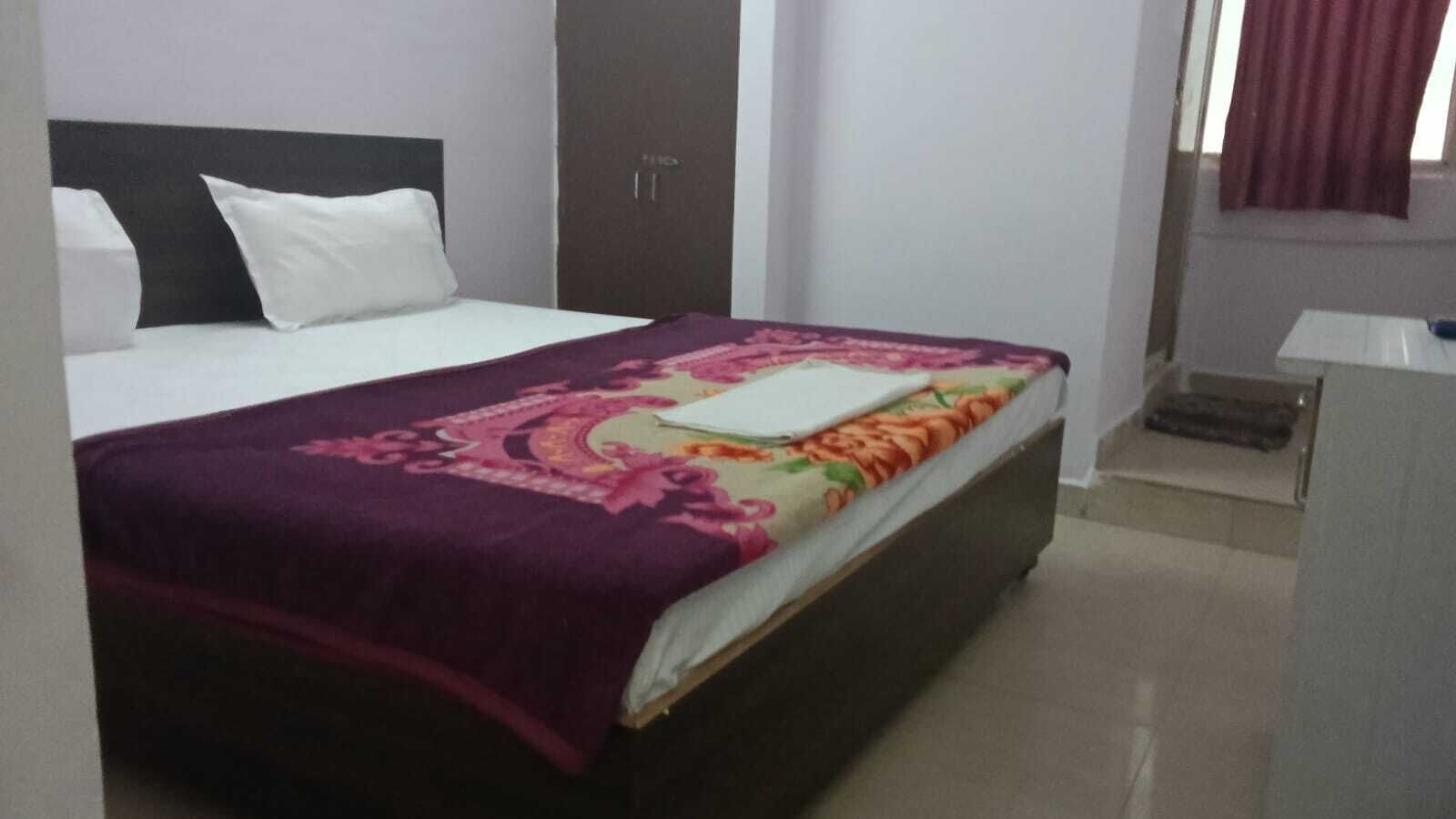 A hotel room with a bed, a wardrobe, and a desk.