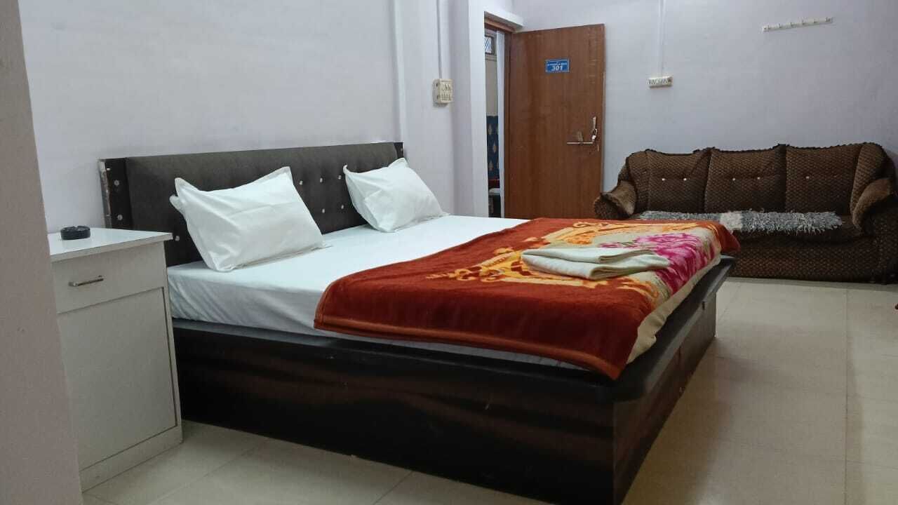 A bedroom with a bed, a nightstand, a sofa, and a door.
