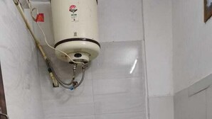 Une petite salle de bain compacte, équipée de toilettes, d’un chauffe-eau et d’un réservoir d’eau.