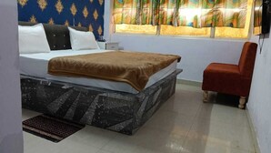 Une chambre à coucher avec un lit, un fauteuil rouge, une fenêtre avec des rideaux et un mur à motifs.