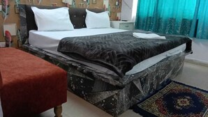 Un lit recouvert d’une couvre-lit à motifs, avec des oreillers blancs et un tapis aux motifs bleus et rouges.