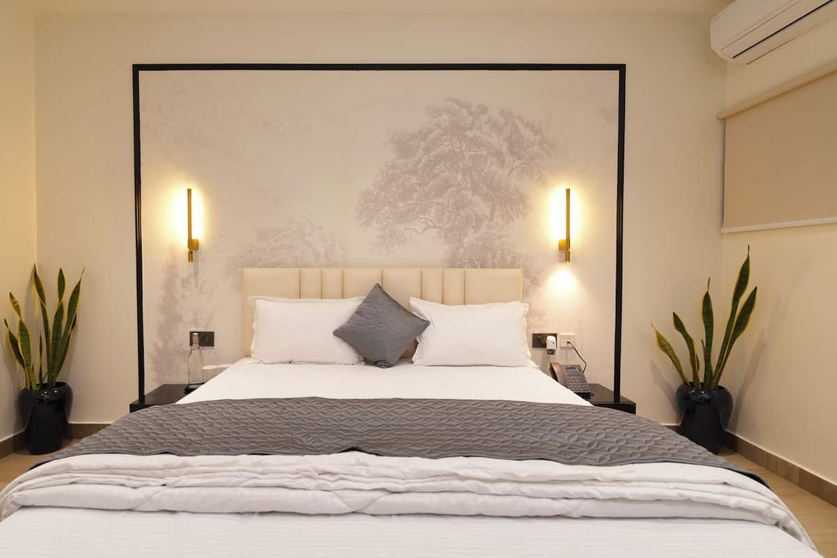 A modern bedroom with a large bed, two bedside tables, a headboard, and wall-mounted lights.