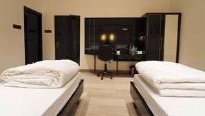 A hotel room with two beds, a desk, and a chair. - Hotel Kuber (Guwahati)