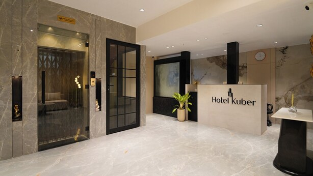 A modern hotel lobby with a reception desk, a seating area, and an elevator. - Hotel Kuber (Guwahati)