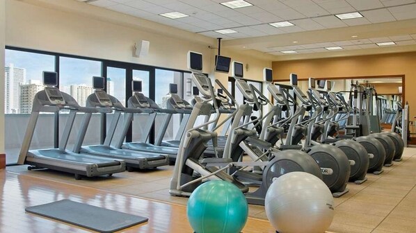 A gym with treadmills, elliptical machines, and exercise balls.