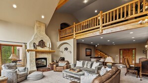 Amplia sala de estar con chimenea, sofás de cuero y una escalera de madera alta.