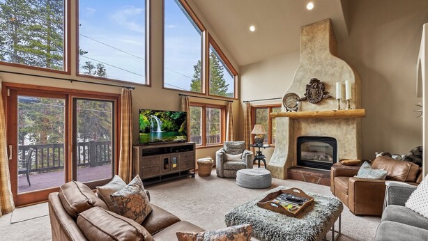 Un salón espacioso con chimenea, ventanas amplias y una zona de estar acogedora.