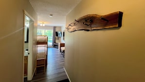 A hallway with a bunk bed, a wooden wall art piece, and a TV mounted on the wall.