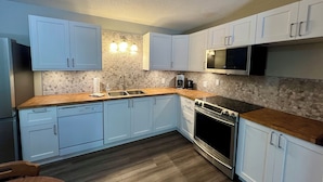 A modern kitchen with white cabinets, a stainless steel oven, and a microwave.