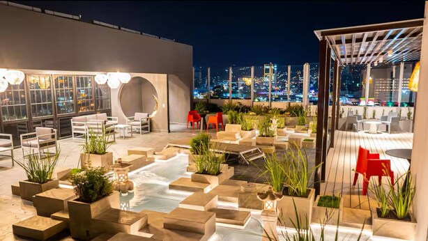 A rooftop terrace with seating, planters, and a city view at night. - Cozy Apartment in San José Costa Rica With Stunning Sunset Views (San José)