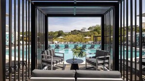 A poolside area with lounge chairs and a small table, overlooking a swimming pool and a landscaped area. - Cozy Apartment in San José Costa Rica With Stunning Sunset Views (San José)