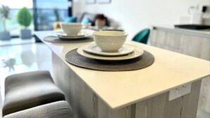 A modern kitchen with a central island, white cabinetry, and a view of the outdoors. - Cozy Apartment in San José Costa Rica With Stunning Sunset Views (San José)