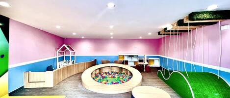 A children's play area with a ball pit, seating, and a slide.