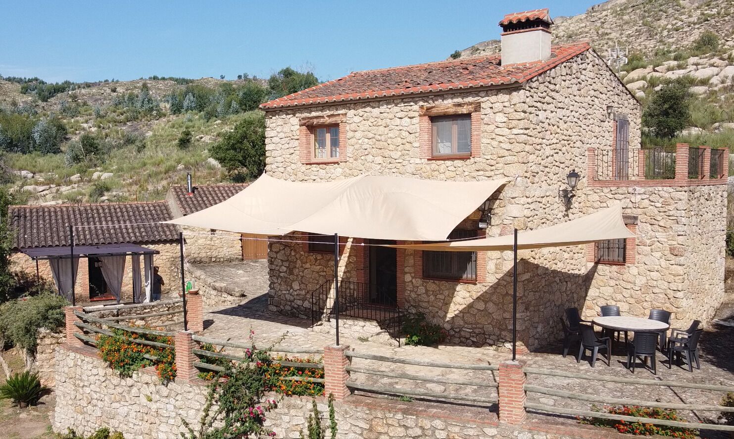 Un edificio de piedra con techo de tejas, mesas al aire libre y un patio cubierto.