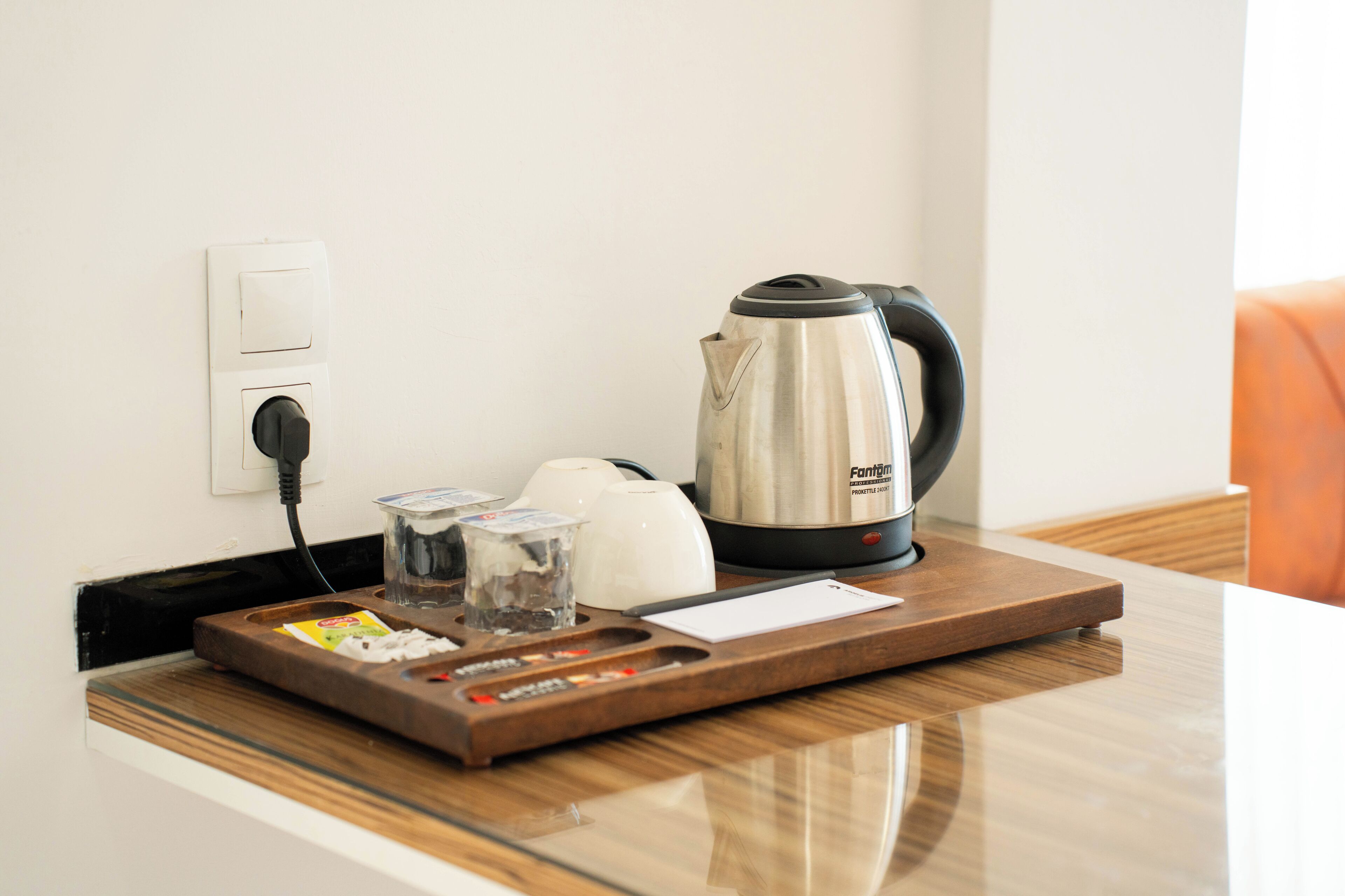 A kitchen counter with a kettle, glasses, and a tray with condiments.
