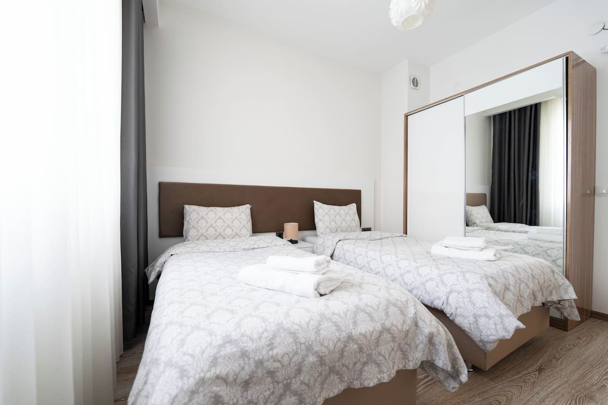 A hotel room with two beds, a large mirror, and a wooden floor.