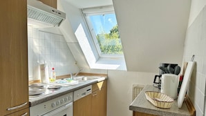 Une cuisine dotée d’une lucarne, d’une cuisinière, d’un évier et d’une machine à café.