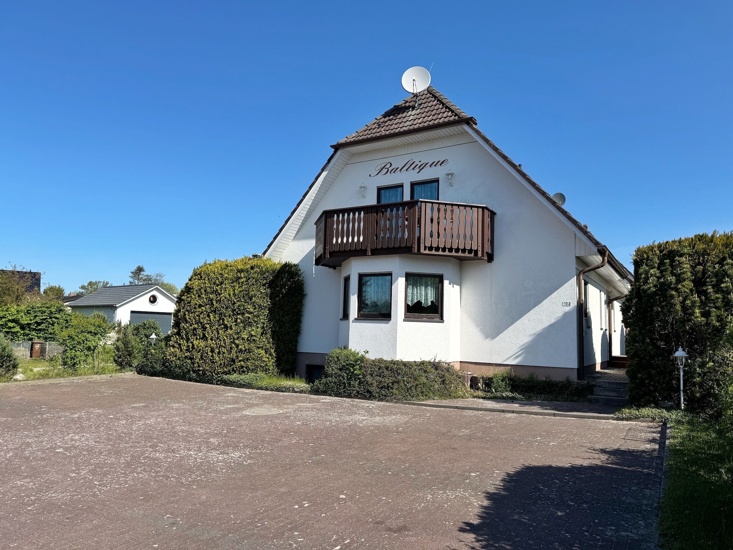 Une maison à deux étages avec un balcon et une antenne parabolique.