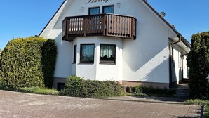 A white building with the name "Baltique" on the facade, a balcony with brown railings, and a satellite dish on the roof. - Vacation apartment Baltique 4 (Glowe)