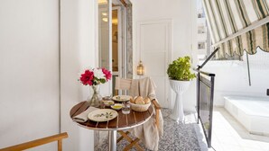 A dining area with a table set for two, a potted plant, and a view of the outside.