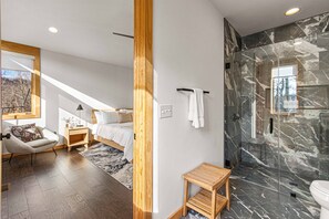 Un dormitorio moderno con cama, mesita de noche y una silla.