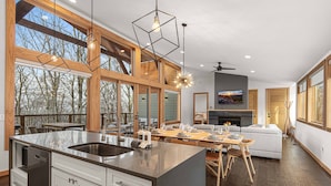 A modern kitchen with a large island, wooden beams, and large windows.