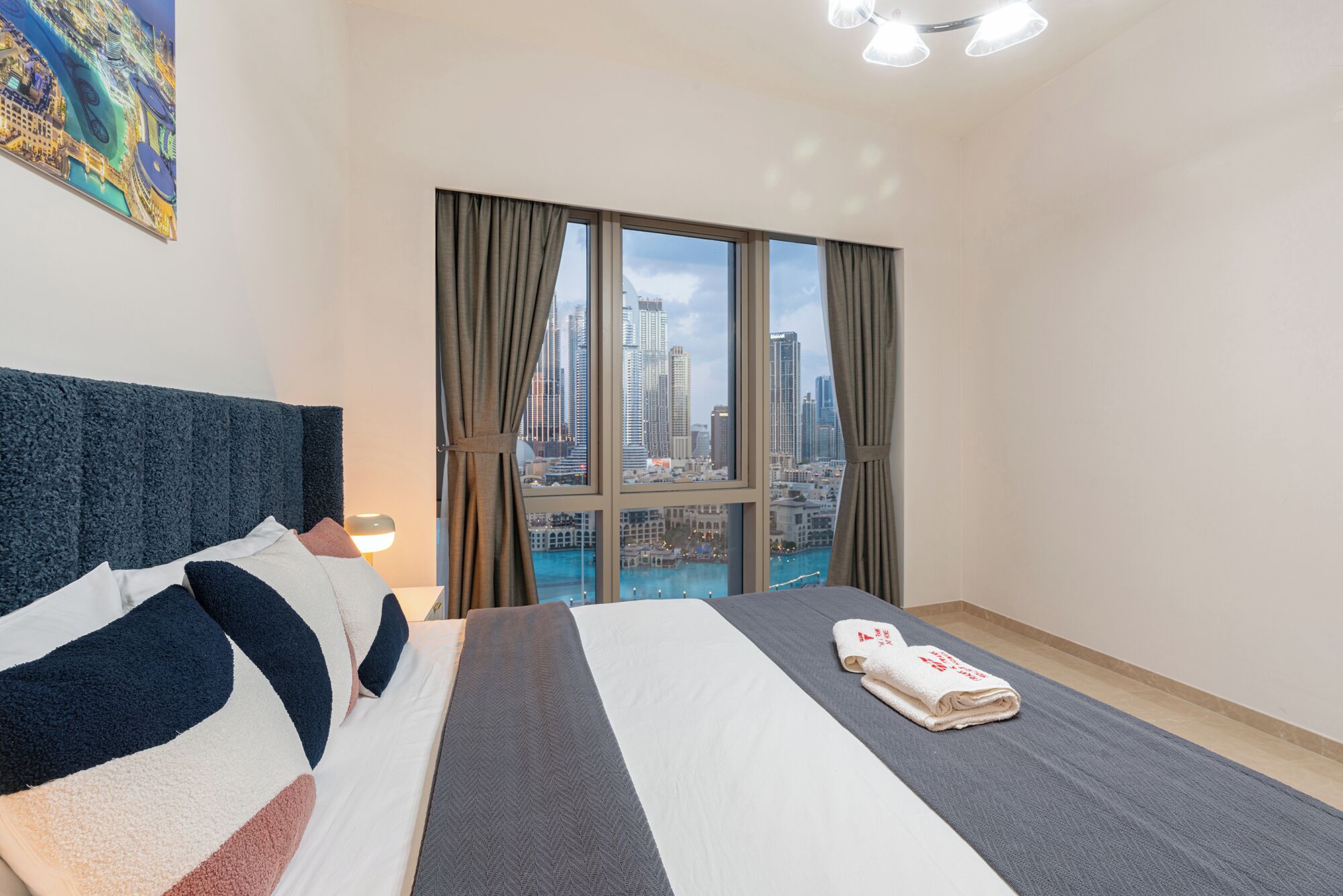 Une chambre d’hôtel avec un grand lit, une vue sur la ville et un tableau accroché au mur.