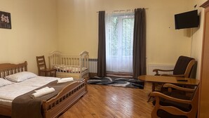Une pièce comprenant un lit en bois, une chaise en bois, une petite table et un téléviseur fixé au mur.