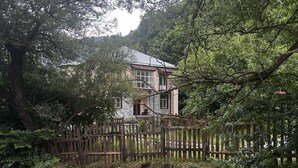 Une maison avec une façade en pierre, un balcon et une clôture en bois.