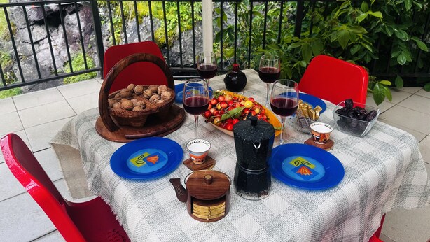 Une table installée à l’extérieur, offrant une vue sur la verdure et agrémentée d’une rambarde.
