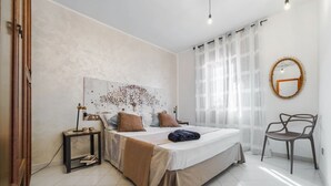 A bedroom with a bed, bedside table, chair, and a wall art piece. - BLUE MARINE: cozy apartment 200 meters from the sea (Ugento)