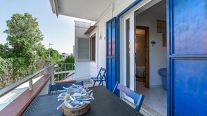 A balcony with a table, chairs, and a pile of white sticks. - BLUE MARINE: cozy apartment 200 meters from the sea (Ugento)