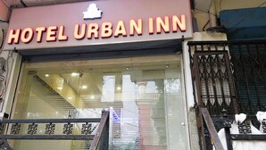 The exterior of Hotel Urban Inn with a prominent neon sign, a glass entrance, and a metal gate. - Hotel Urban Inn (Prayagraj)