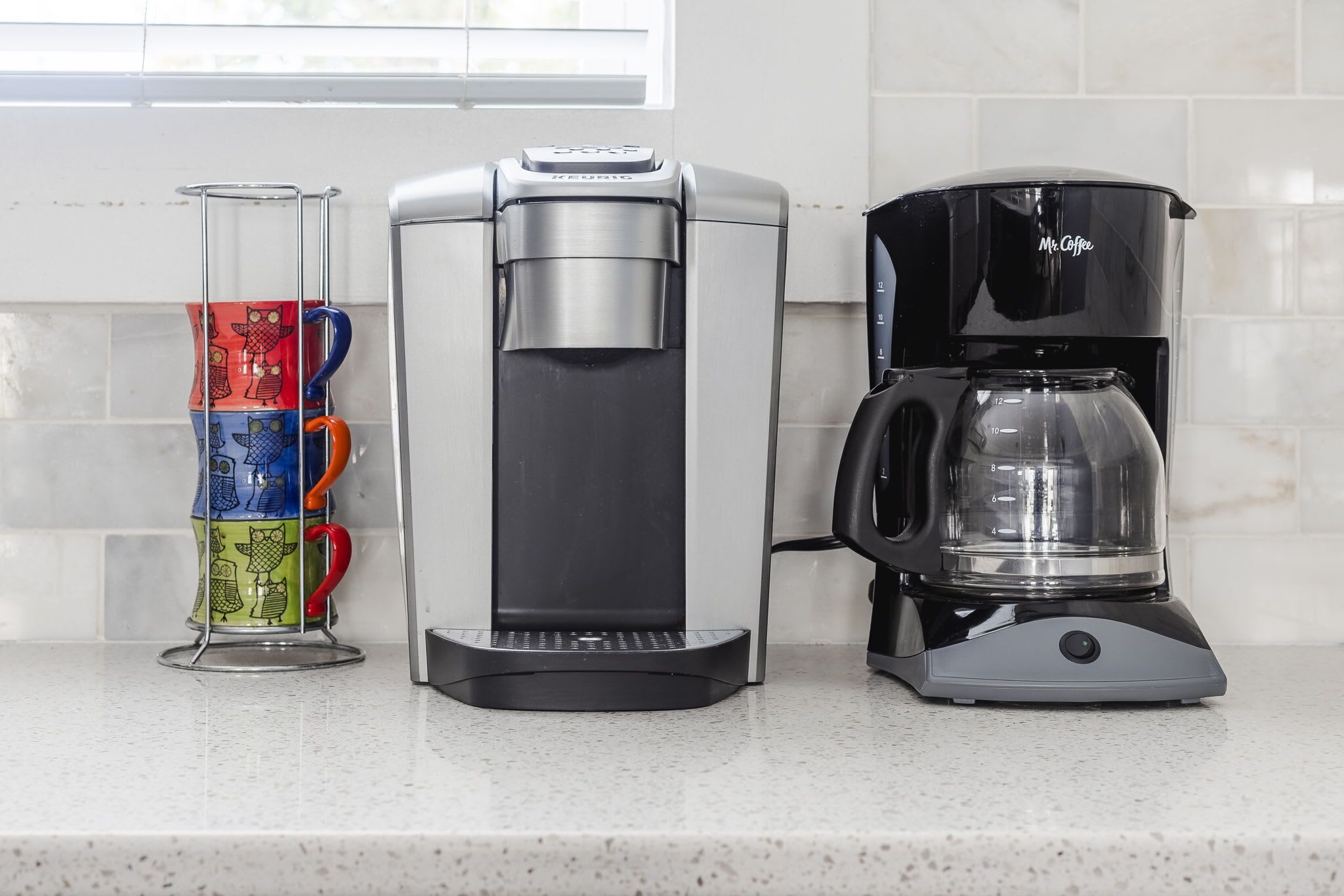 Una encimera de cocina con tres cafeteras y un portavasos.