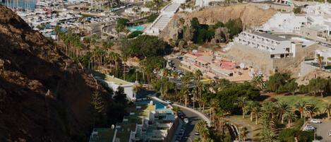 A coastal resort with a marina, buildings with balconies, and a view of the sea.