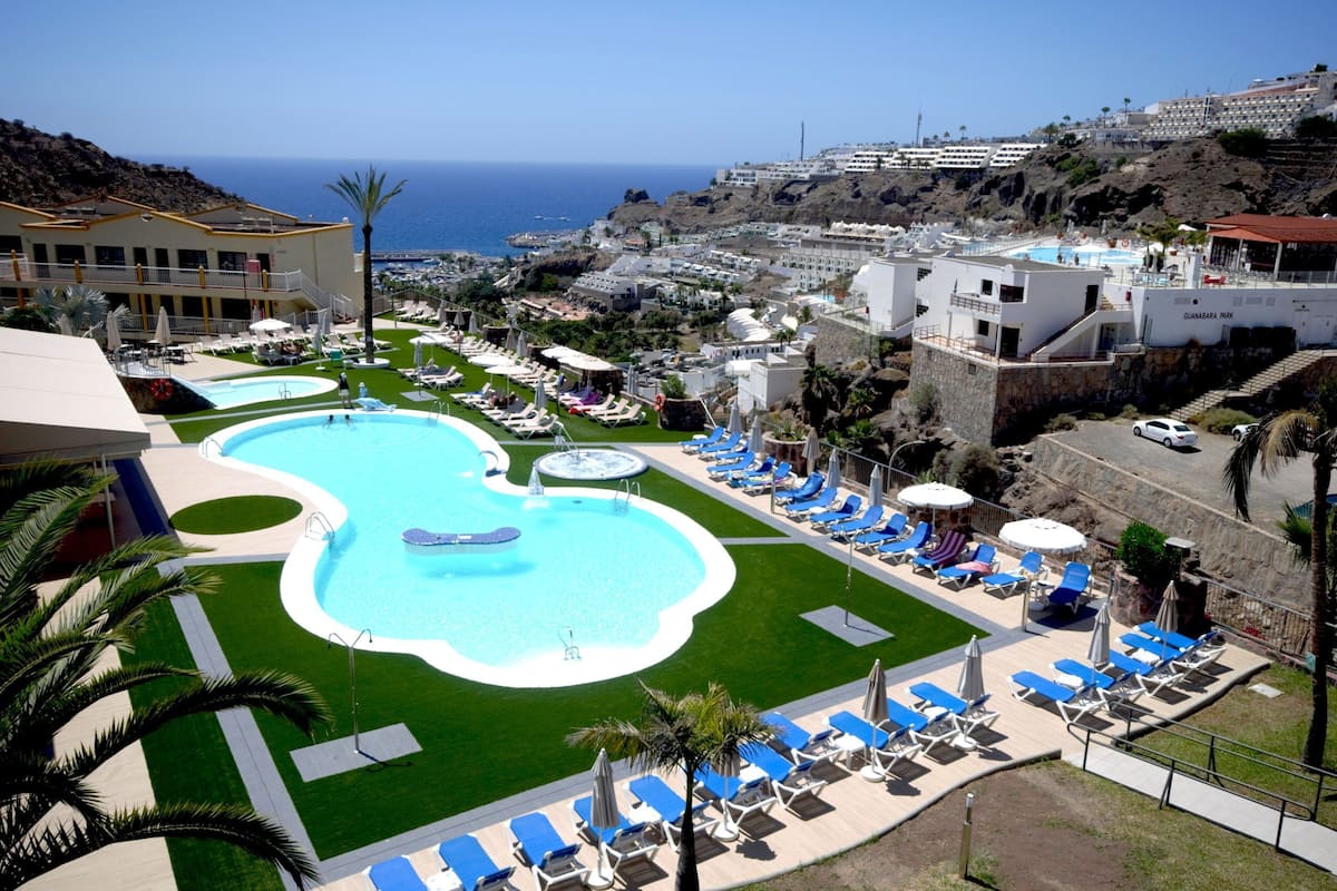 Un resort con varias piscinas, tumbonas y vistas al océano.