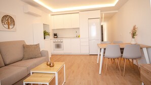 A modern living room with a sofa, coffee table, and dining area with chairs and a table. - Natural Park (Mogán)