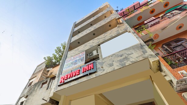 A multi-story building with a prominent sign for 'Revive Inn' indicating it is a hotel. - Hotel Revive By The Premium Villa (New Delhi)