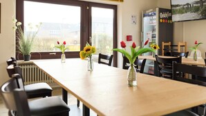 Ein Essbereich mit einem langen Tisch, Stühlen und Vasen mit Blumen.