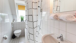 A modern bathroom with a shower, toilet, and sink. - Quartier 14<br>Apartment in a quiet location and access to sea time (Büsum)
