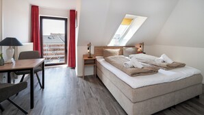 A modern hotel room with a large bed, a desk, and a view of the city through a skylight. - Quartier 14<br>Apartment in a quiet location and access to sea time (Büsum)