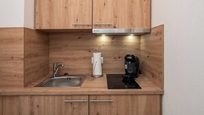 A compact kitchen with wooden cabinetry, a stainless steel sink, a Bosch coffee maker, and a paper towel dispenser. - Quartier 16<br>Apartment in a quiet location and access to sea time (Büsum)