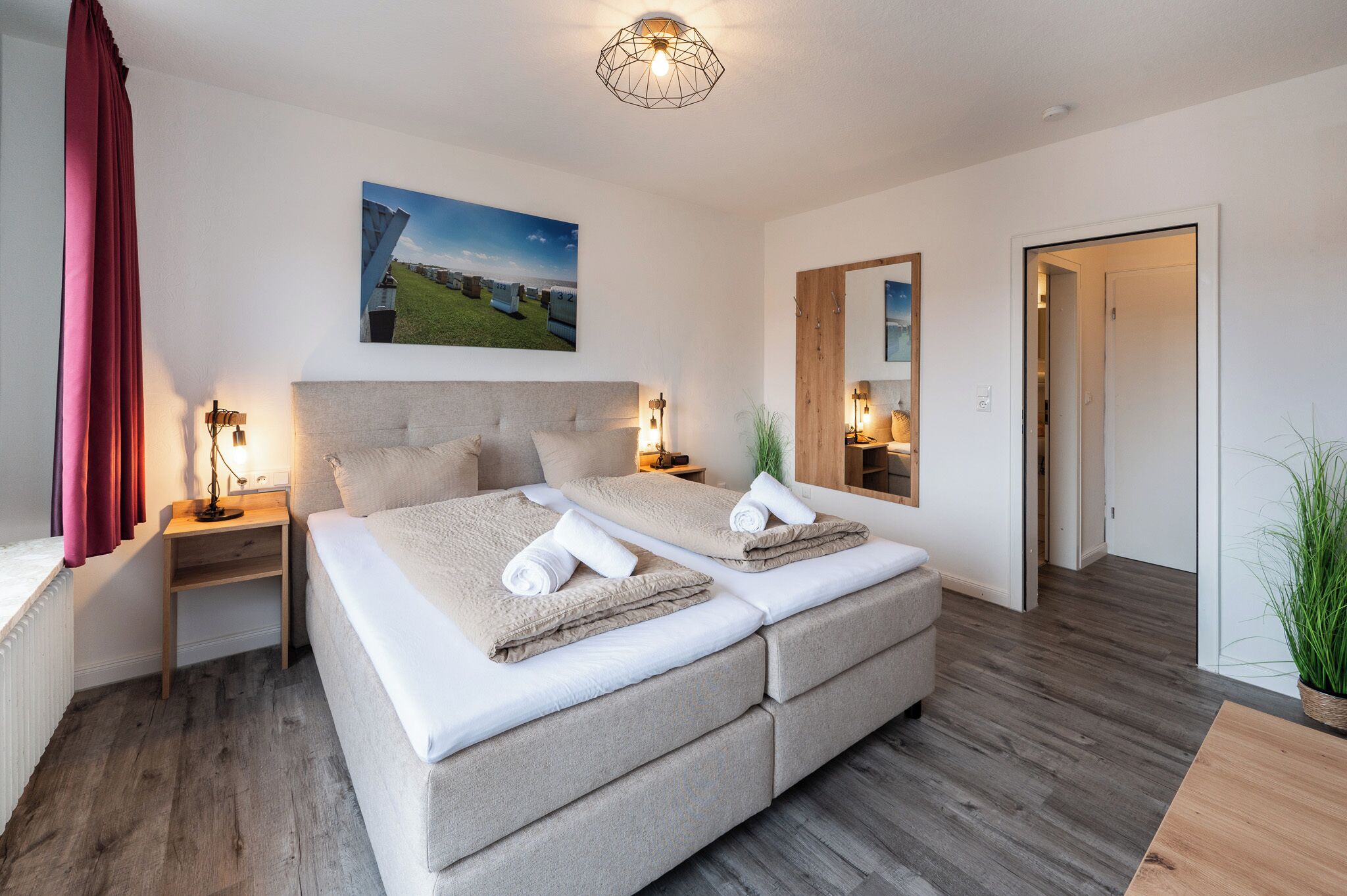 Een moderne slaapkamer met een groot bed, nachtlampjes, een schilderij en een spiegel.